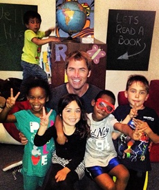 Picture of Roy Moranz volunteering, reading with kids in Emergency Transitional Housing.